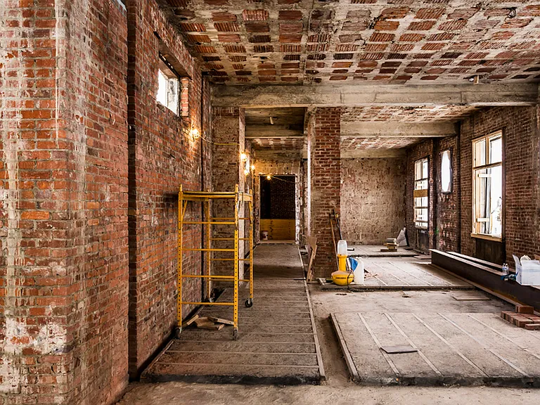 Before: Galley room with exposed brick during renovations