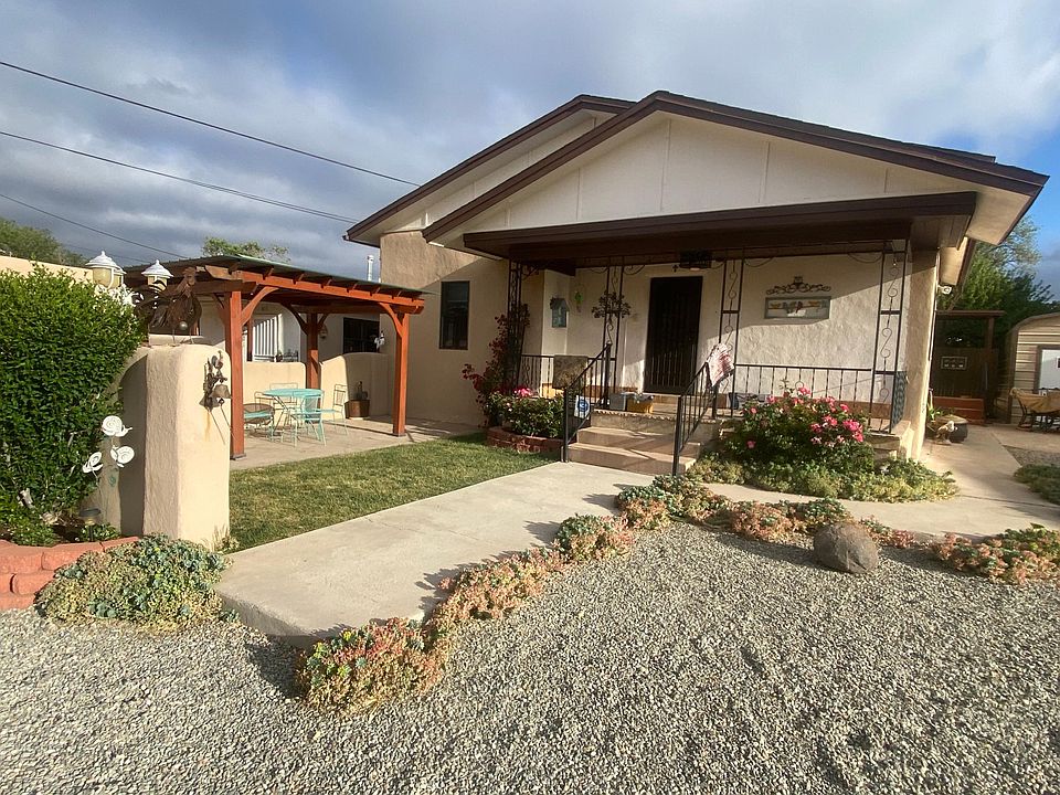 Exterior with views of private flagstone patio, pergola, outdoor table, grass and flowering beds.