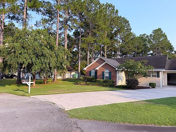 Front exterior with mature trees, attractive landscaping, and a wide driveway