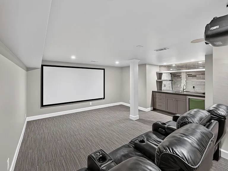 Large home theatre with two rows of movie seating that recline. Built-in bar provides ample entertaining options. All video equipment and seating included.
