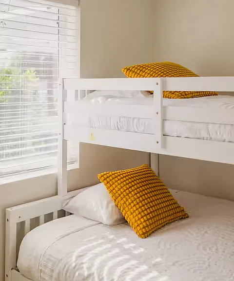 Bedroom built for fun! With a single-over-double bunk bed plus trundle, soft, cozy bedding, and plenty of sunlight, it's a perfect hangout for kids. Sleepovers, group stays, or just chilling_this room makes it all comfy and playful.