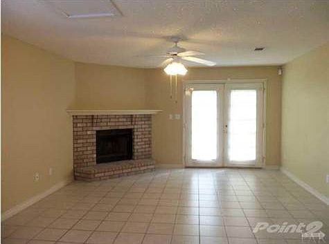 Spacious great room has a wood-burning fireplace and double French doors to the patio.