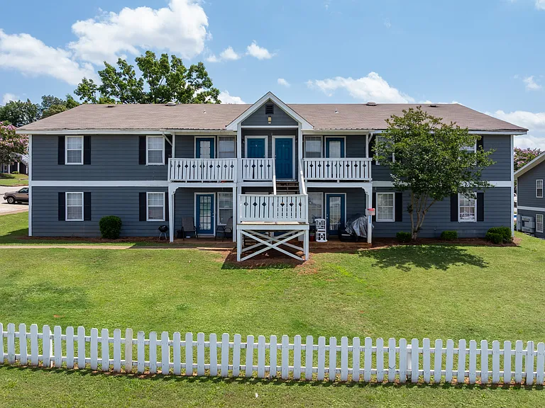Charming two-story apartment homes with white picket fencing in a residential setting, professionally operated by Highlands Vista Group.