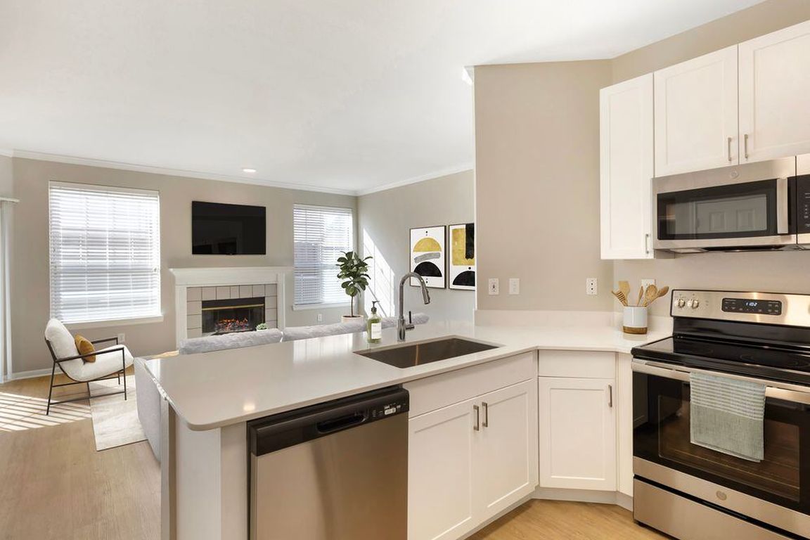 Renovated Package I kitchen with stainless steel appliances, white speckled quartz countertop, white cabinetry, and hard surface flooring