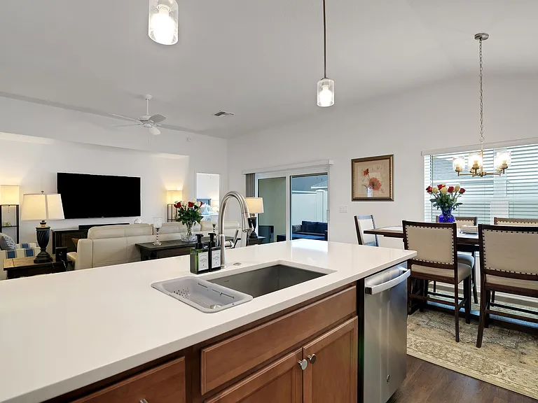 A View of the Open Area of the House through the Kitchen Island with the Sink and Dishwasher, Overseeing the Living Room and the Dining Room.