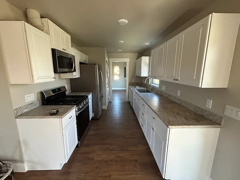 Galley kitchen with stainless steel appliances and granite countertop