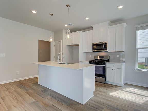 Modern kitchen in new construction home with large island, quartz countertops, and pendant lighting.