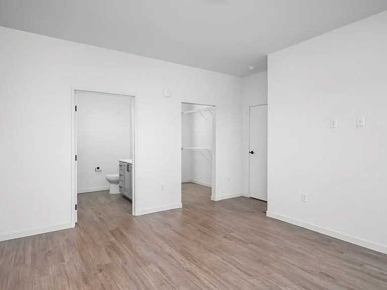 Bright and spacious bedroom featuring sleek hardwood floors, a walk-in closet, and an en-suite bathroom. Bright and spacious bedroom featuring sleek hardwood floors, a walk-in closet, and an en-suite bathroom.