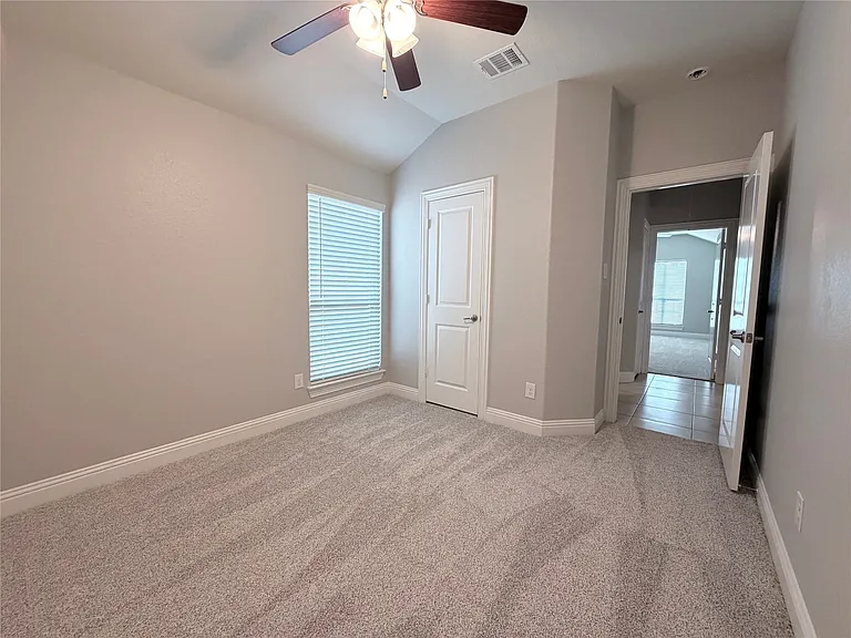 This other spacious secondary bedroom offers a comfortable and inviting atmosphere, highlighted by impressive vaulted ceilings that add architectural interest to the room. The space is equipped with a modern ceiling fan for optimal climate control, featur