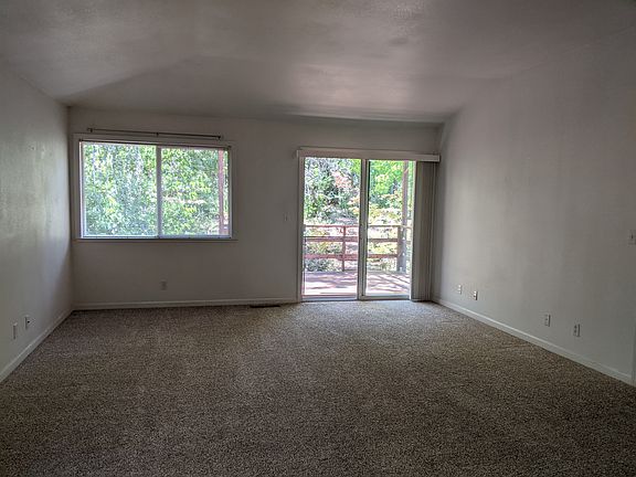 Spacious living room, with sliding glass door and beautiful view out to the back deck and forested yard.