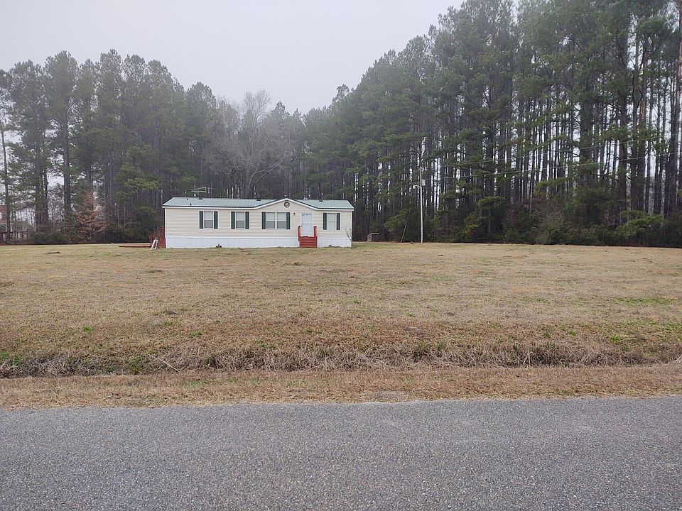 View from the street with large overhead light and pump house in the background. Driveway is out of sight to the left.