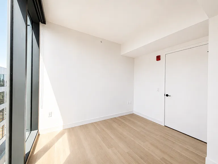 Sunlit bedroom at Stead 220 in Fulton Market with floor-to-ceiling corner windows, wide-plank flooring, and abundant natural light, offering a bright and private retreat.