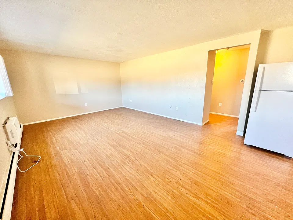 Bright living room with expansive hardwood floors and a modern refrigerator. Bright living room with expansive hardwood floors and a modern refrigerator.