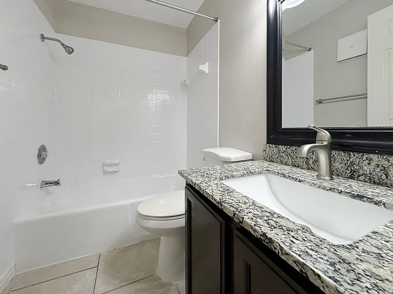 Stylish bathroom featuring granite vanity and tub-shower combo at Los Cedros Apartments in Brownsville, TX.