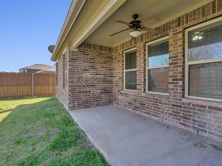 Brick exterior featuring a covered concrete patio with a ceiling fan