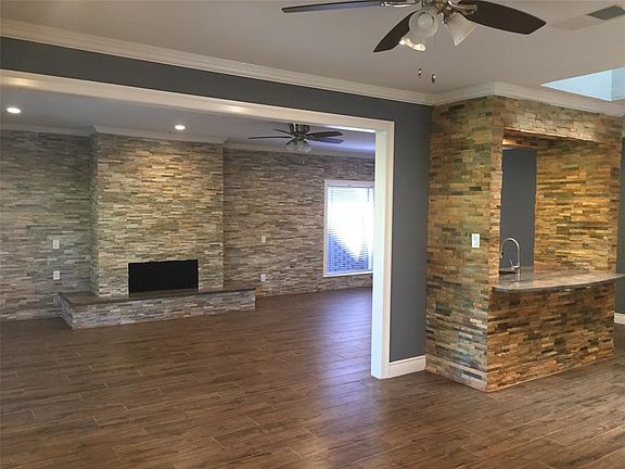 STONE FIREPLACE WALL IN LIVING ROOM. NOTICE STONE WET BAR THAT SEPARATES LIVING ROOM FROM DINING ROOM.
