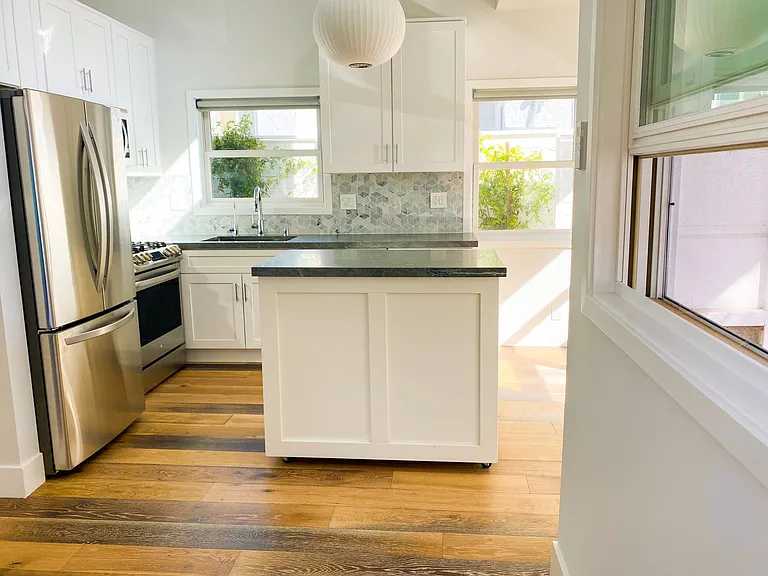 Large island with cabinets, trash, and recycling containers.