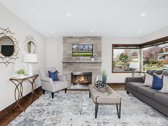 The living room features large windows, elegant gas fireplace and hardwood floors. >