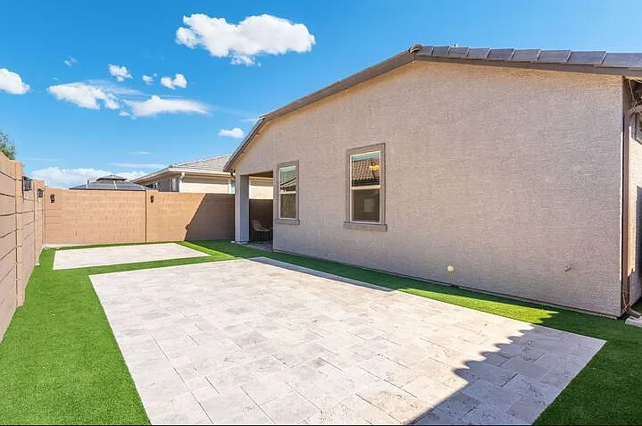 Simple and peaceful fenced-in backyard with turf and tile.