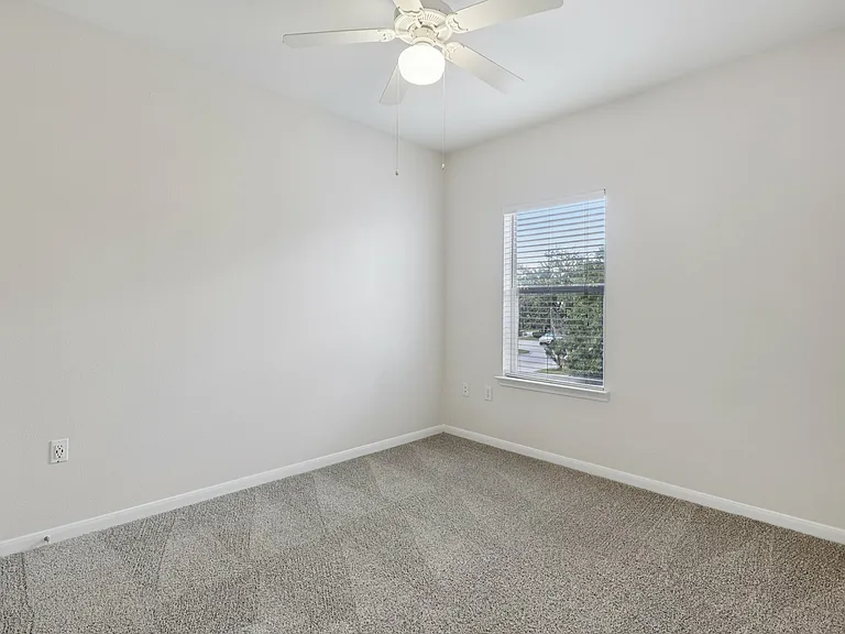 Bright and airy room with plush carpeting, large window, and ceiling fan, perfect for a cozy retreat. Bright and airy room with plush carpeting, large window, and ceiling fan, perfect for a cozy retreat.