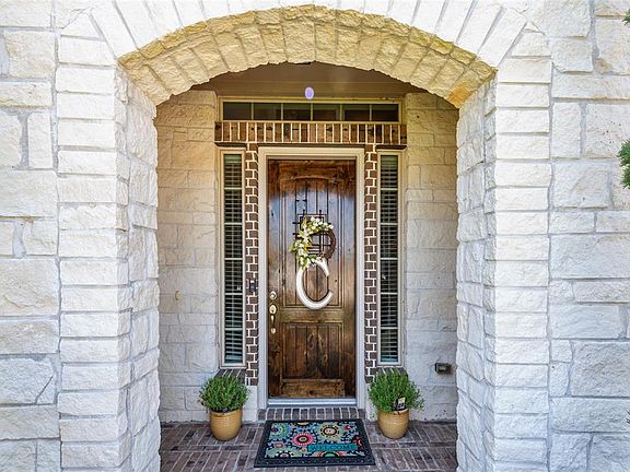 A winding sidewalk leads to a picture perfect front porch with design elements like charming stone archway, brick border and wood door w/wrought iron!