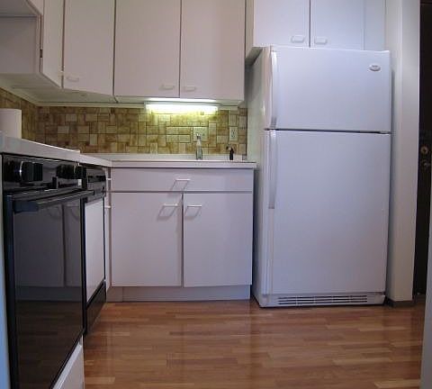 Kitchen with hardwood floors and overhead indirect lighting.