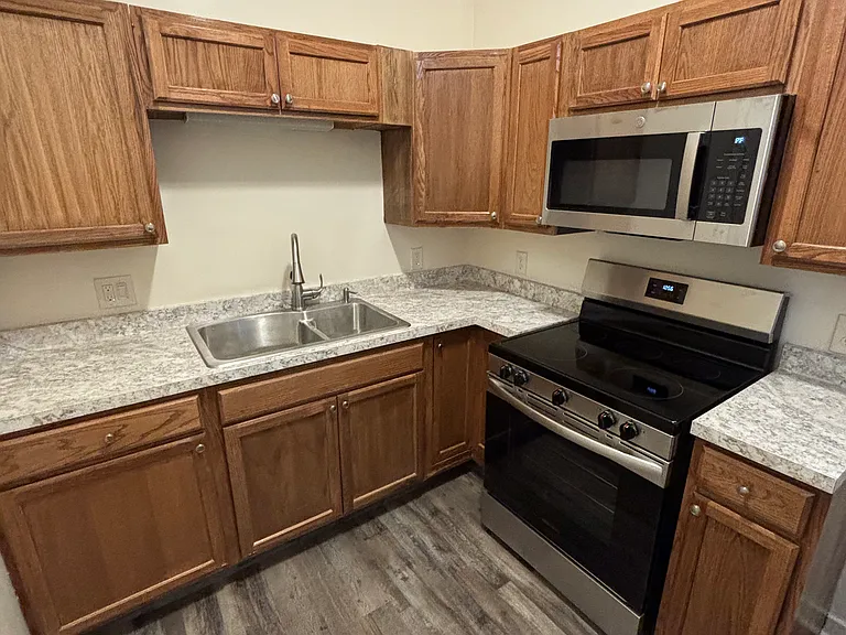 Brand new kitchen featuring all new appliances, stove, microwave & refrigerator.