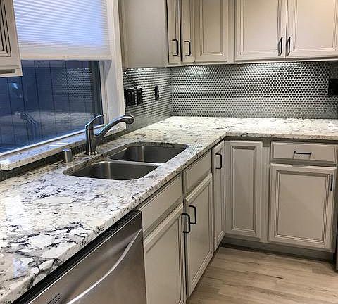 KITCHEN WITH GRANITE COUNTER TOPS SINK AND DISHWASHER.