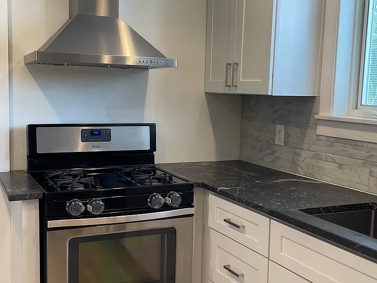 Perfect setup for home cooking with a gas range, stainless steel hood, and updated kitchen finishes.