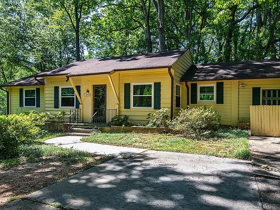 Wide driveway for parking. Small fence on right conceals the trash cans.