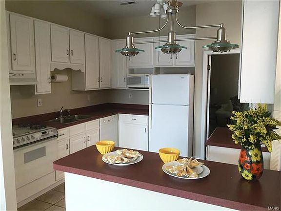Kitchen with ceramic flooring and counter for 2 kitchen bar stools.