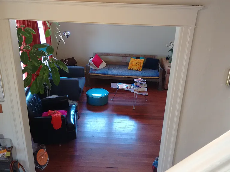 view of living room, including original hardwood floors, from stairwell