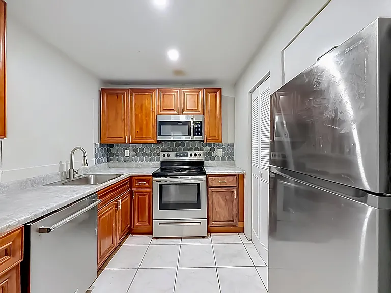 Efficient galley kitchen with ample wood cabinetry, stainless appliances, tile backsplash, and generous counter space.