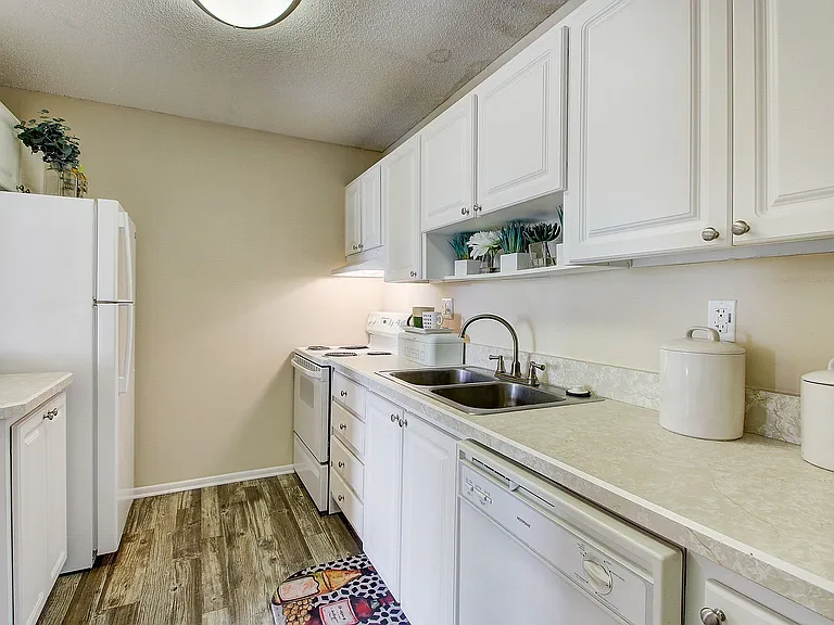 Charming kitchen with bright white cabinetry, cozy wooden flooring, and sleek modern appliances.