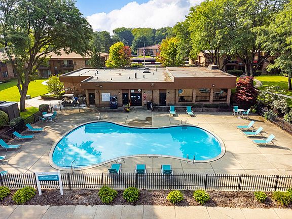 Heated pool equipped with comfy lounge chairs at Westwood Village Apartments in Westland, MI
