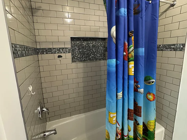 Tub/shower combo with subway-tile surround, decorative accent band, and built-in niche shelving for bath essentials.