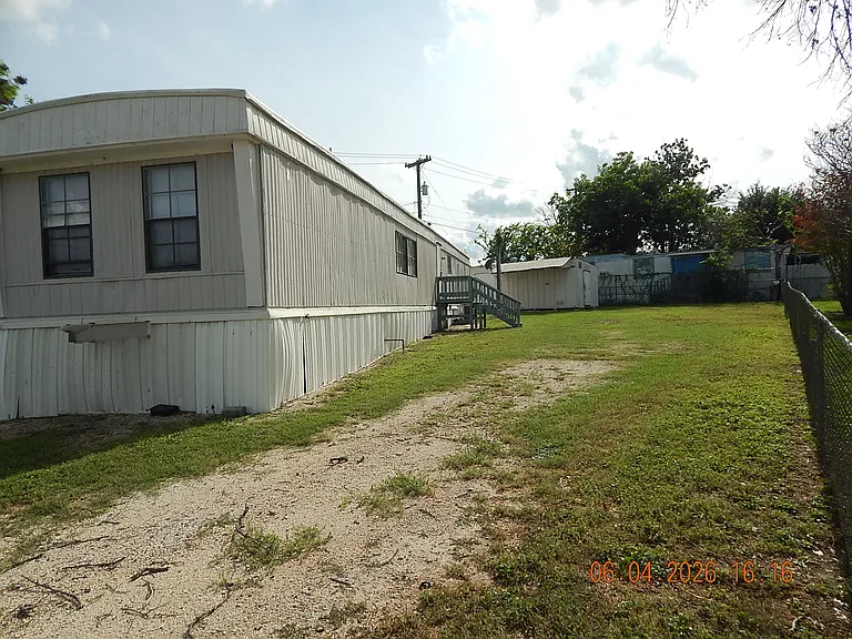 View from vehicle entrance gate - back door home entrance with deck - storage building behind home
