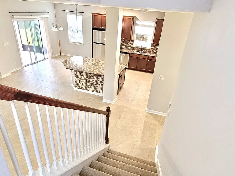 Stair case view of living and kitchen