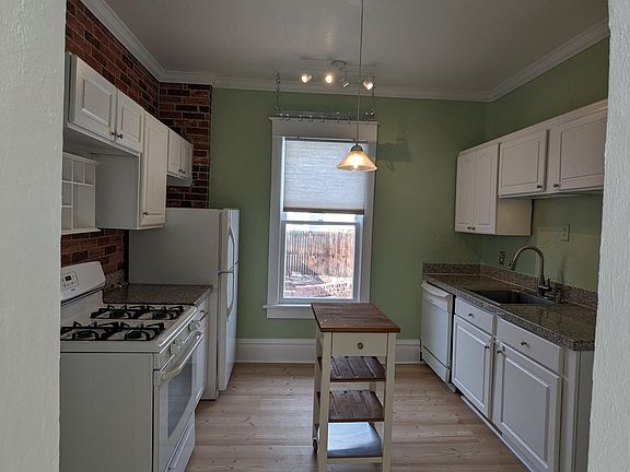 kitchen features new paint and flooring, gas stove, dishwasher, hanging pot rack and kitchen cart