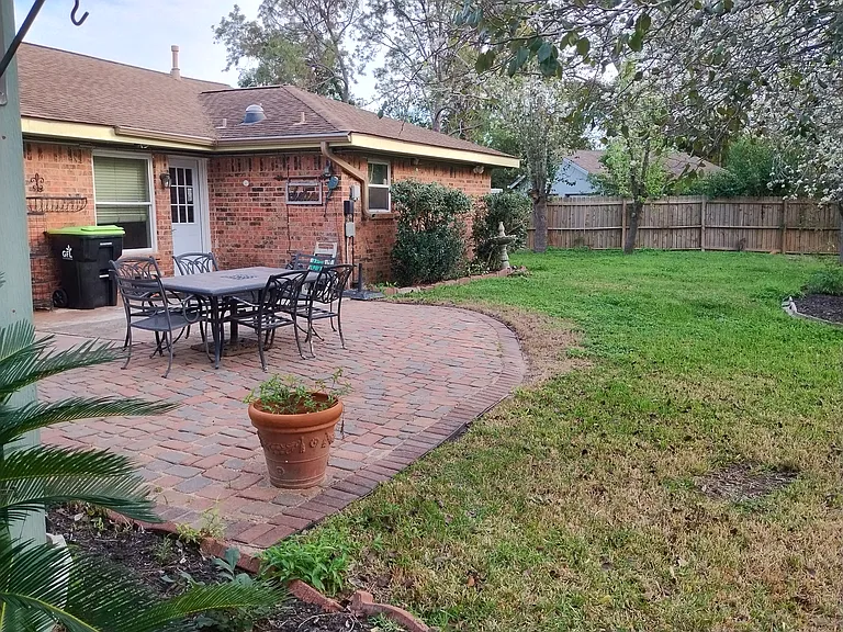 Backyard patio and backyard. Ornamental Bradford Pear Trees are the ones in bloom and along the back fence line.