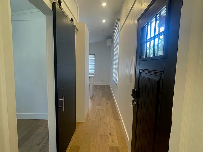 Looking down the hallway towards kitchen/living room with office/study on left and entry door on right.