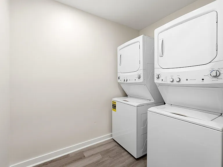 Dedicated laundry area with stacked washer and dryer and durable flooring for easy day-to-day upkeep.