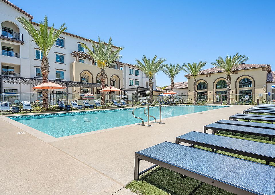 Resort-style pool with chaise lounges, shade umbrellas and soft lounge seating.