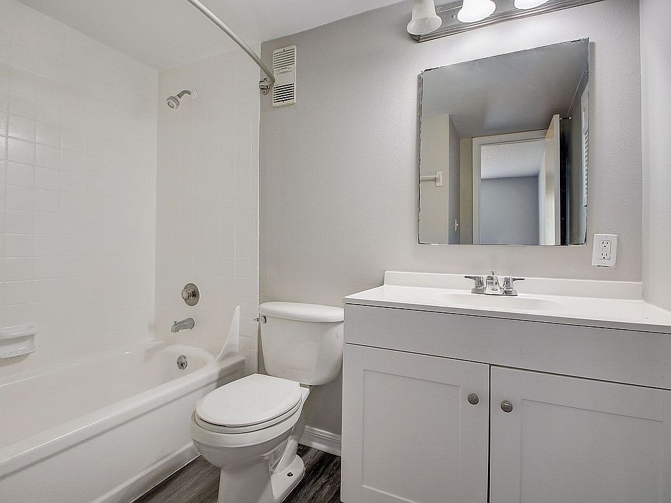 Modern bathroom with sleek white fixtures, featuring a spacious bathtub, elegant vanity, and large mirror, offering a bright and inviting atmosphere.