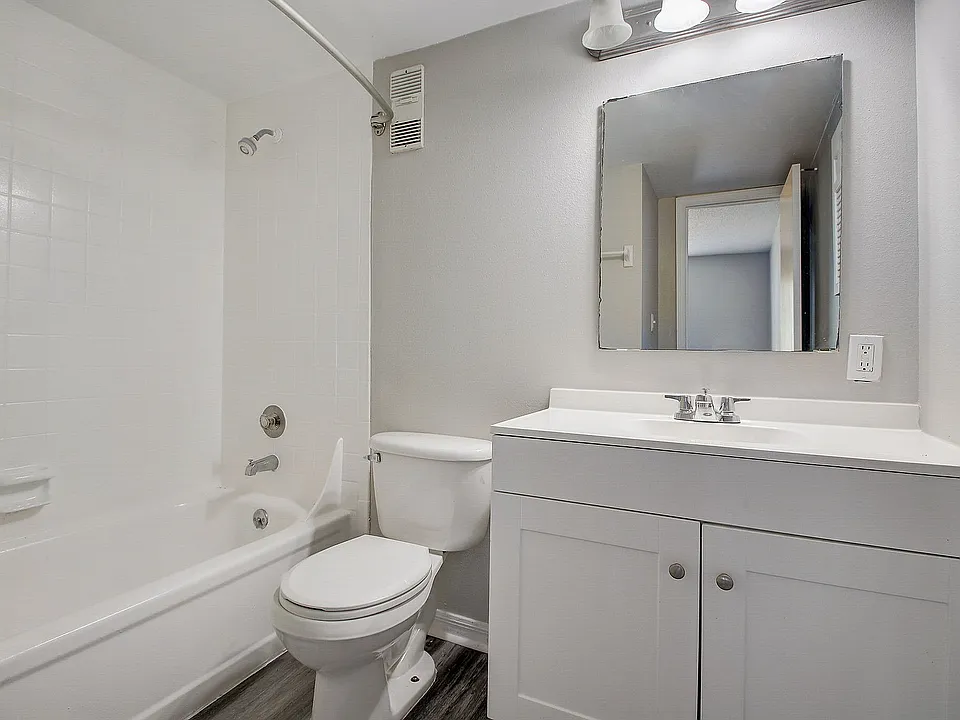 Modern bathroom with sleek white fixtures, featuring a spacious bathtub, elegant vanity, and large mirror, offering a bright and inviting atmosphere.