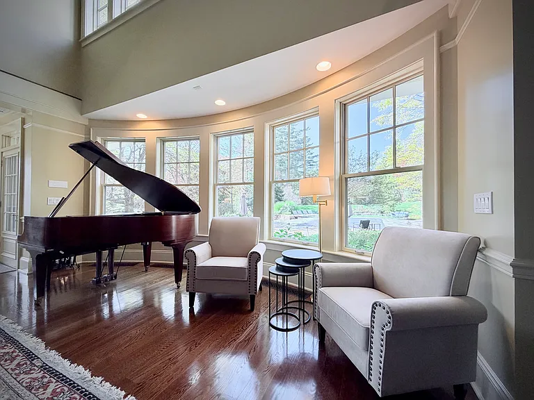 View of the richly decorated great room with seating for up to seventeen, a massive stone fireplace, and a grand piano.