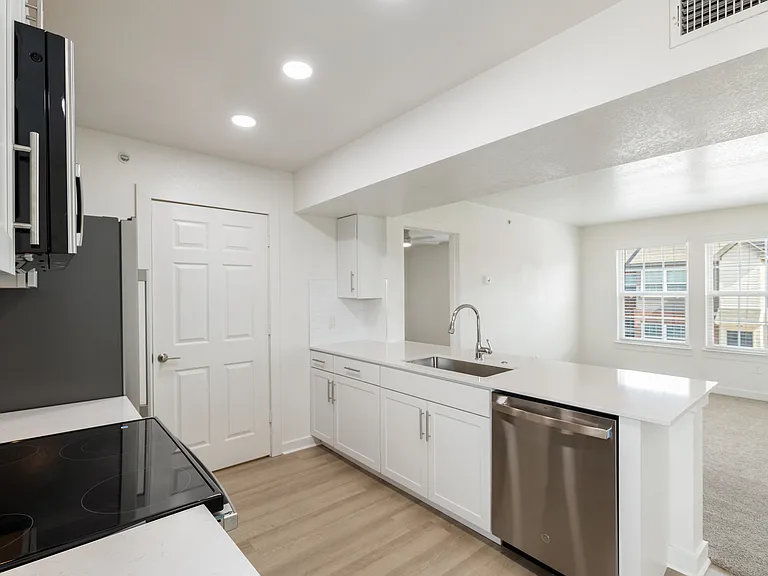 Bright kitchen with modern appliances, sleek countertops, and an open layout leading to a cozy living room with large windows. Bright kitchen with modern appliances, sleek countertops, and an open layout leading to a cozy living room with large windows.