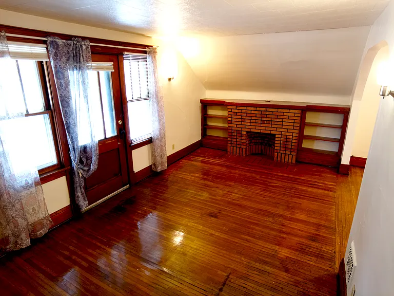 Living room - entrance to the porch/patio is through the door on the left. Original hardwood floor.