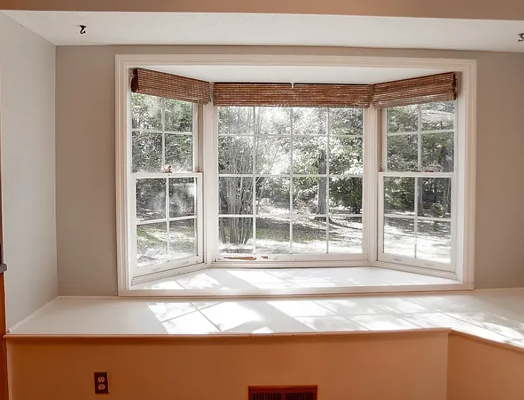 Large breakfast nook with bay window and built-in seating overlooks the shaded backyard