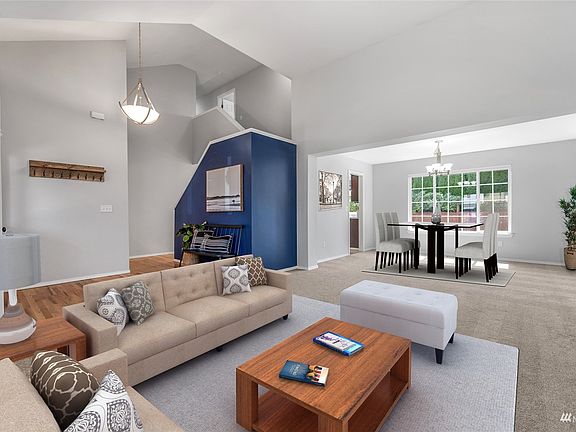 Digitally staged living room with vaulted ceilings>